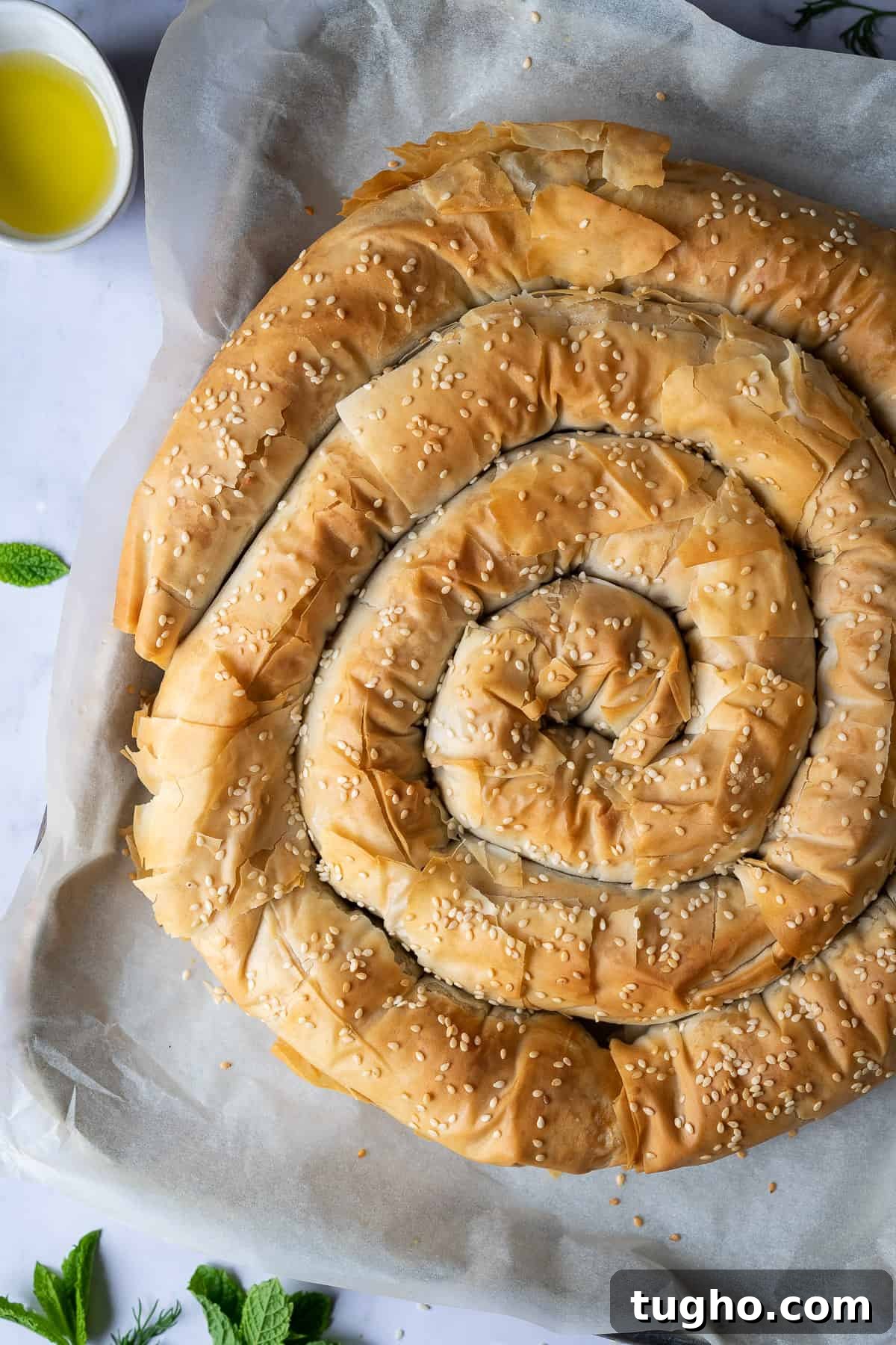 Vegan spanakopita spiral - this impressive vegan spinach and cheese filo pie consists of a soft, cheesy, salty, herby spinach filling encased in crisp phyllo pastry. It's a real crowd pleaser that is much easier to make than it looks! #veganbaking #dairyfree #veganmeal Close up fo vegan spanakopita spiral