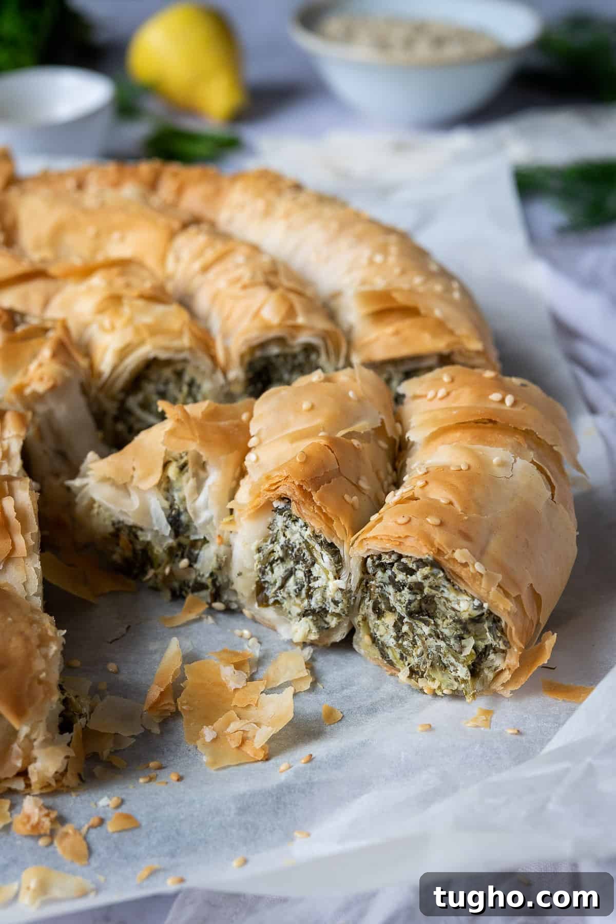 Vegan spanakopita spiral - this impressive vegan spinach and cheese filo pie consists of a soft, cheesy, salty, herby spinach filling encased in crisp phyllo pastry. It's a real crowd pleaser that is much easier to make than it looks! #veganbaking #dairyfree #veganmeal close up of a slice of vegan spanakopita spiral