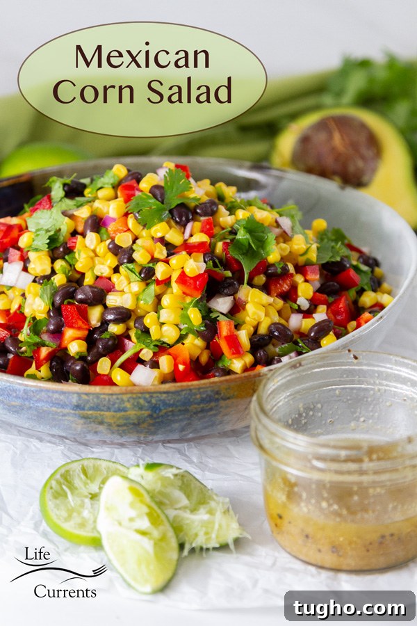 salad in a bowl with squeezed limes, a mason jar of dressing, and an avocado around it.