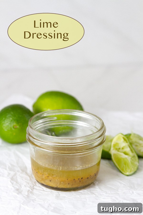 lime dressing in a small mason jar with limes around it plus squeezed lime wedges.