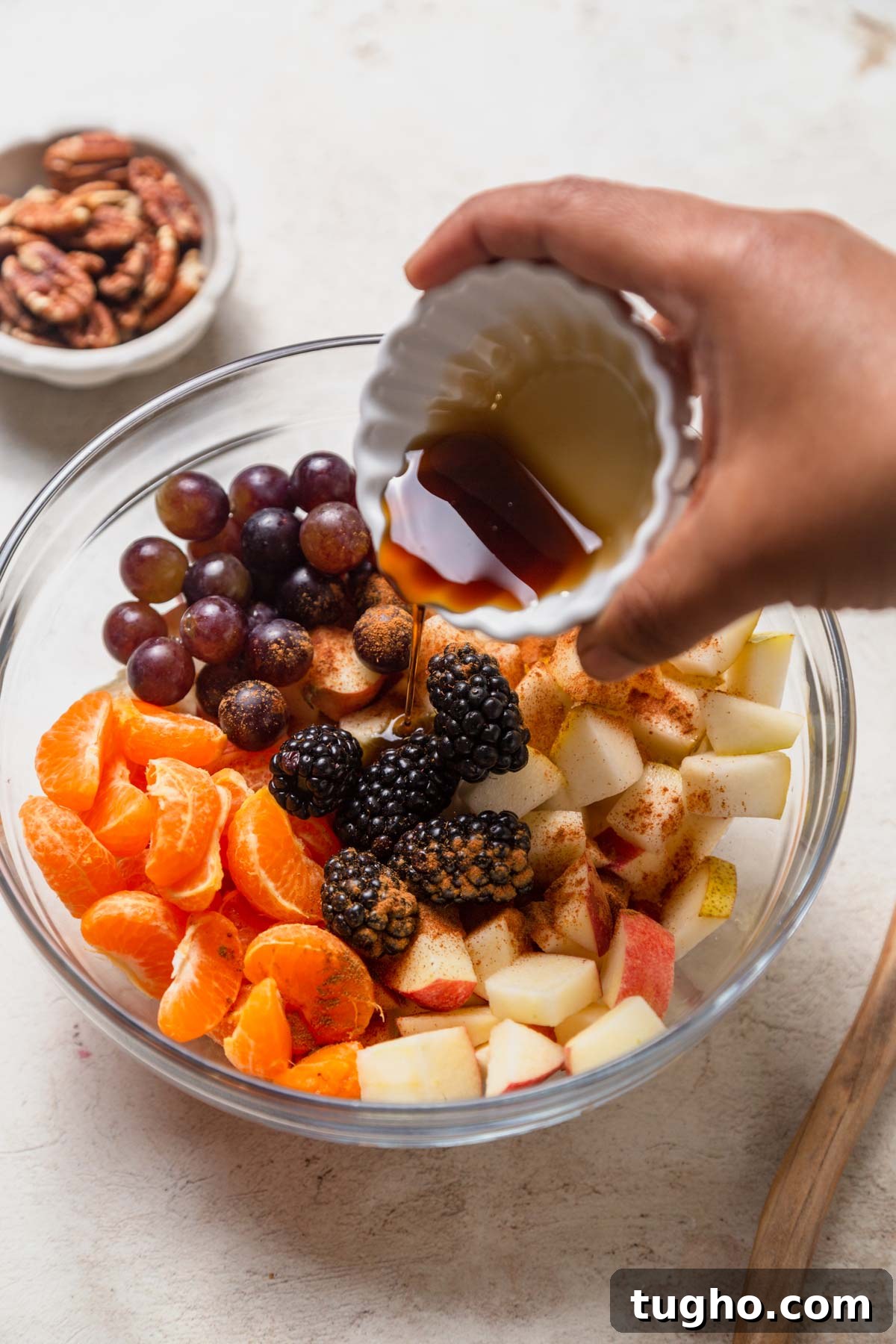 adding maple syrup to the thanksgiving fruit salad.
