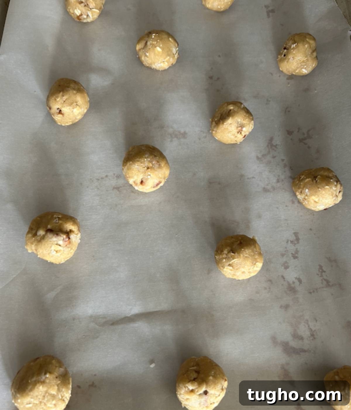 Pecan Coconut cookies rolled into cookie balls on parchment paper lined sheet.