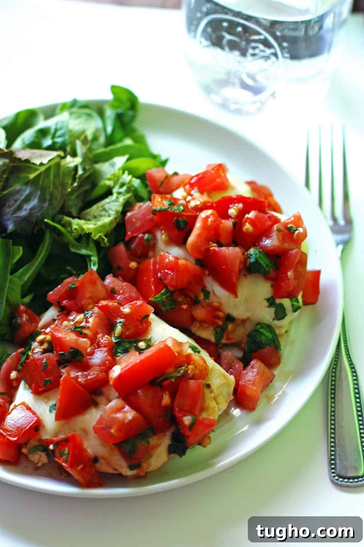 Grilled Chicken Topped with Fresh Tomato Bruschetta 2 A plate of bruschetta chicken with mozzarella, tomatoes, and basil on top and a side salad.
