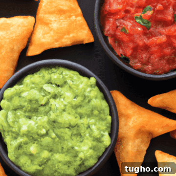 best keto tortilla chips on a black background with guacamole and salsa nearby