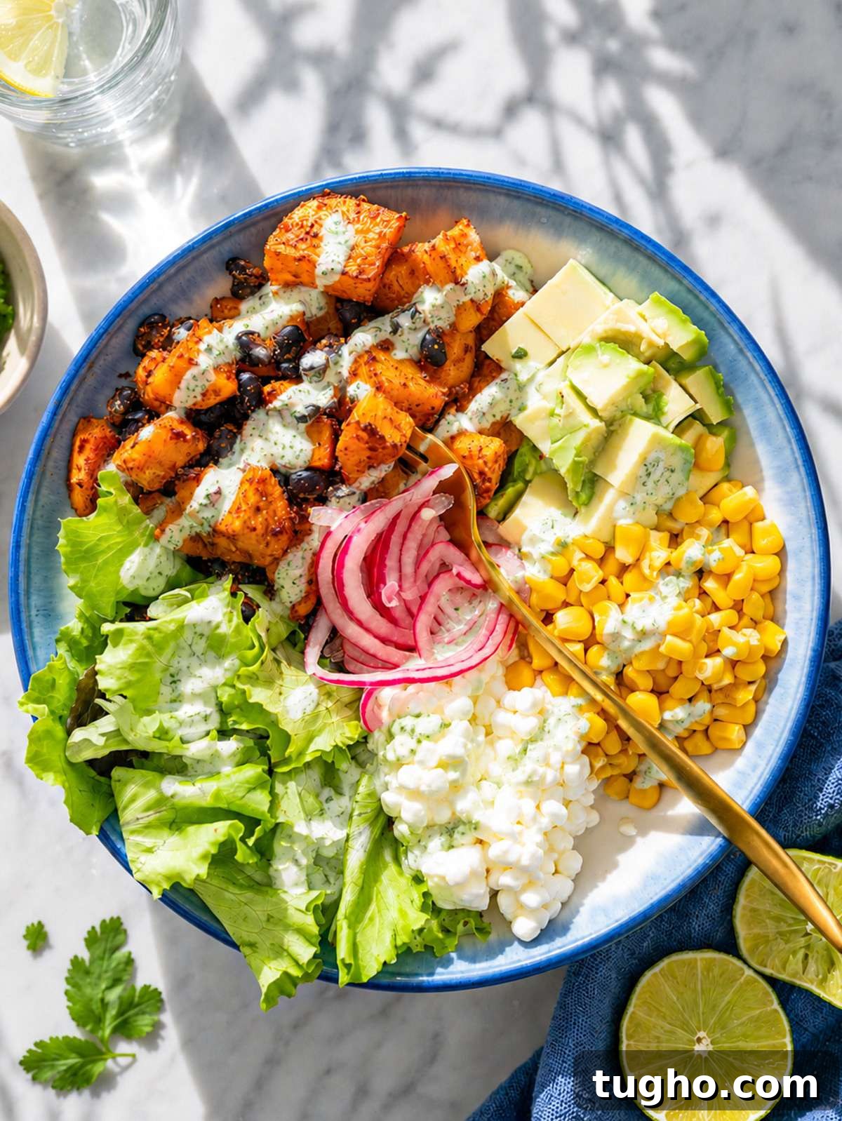Black bean sweet potato bowl topped with avocado and pickled onions in natural light.