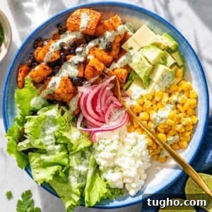 Sweet potato black bean bowl served with fresh toppings on a white marble table.