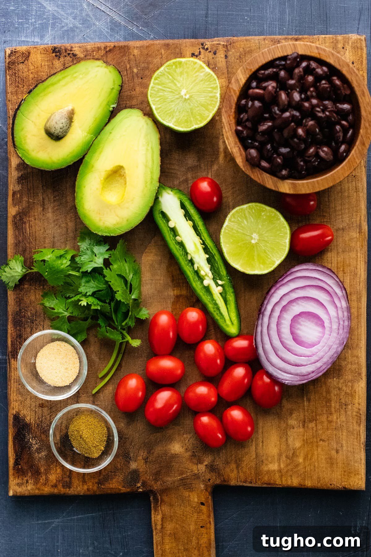 Ingredients for black bean salsa arranged on a brown wooden cutting board.