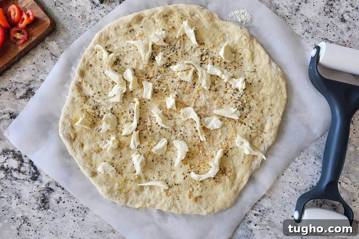 Pizza dough with olive oil, seasonings, fresh mozzarella cheese and parmesan cheese.