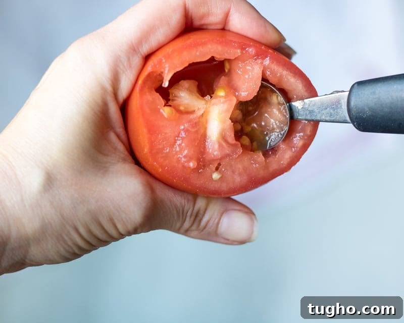 Using a melon baller to seed tomatoes.
