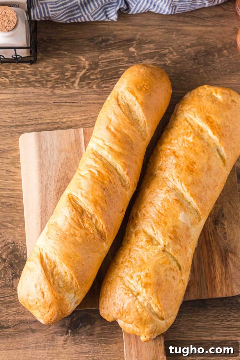 French Baguette Recipe: Make Two Loaves at Home 2 Two golden-brown homemade French Bread baguettes on a cutting board - Hostess At Heart