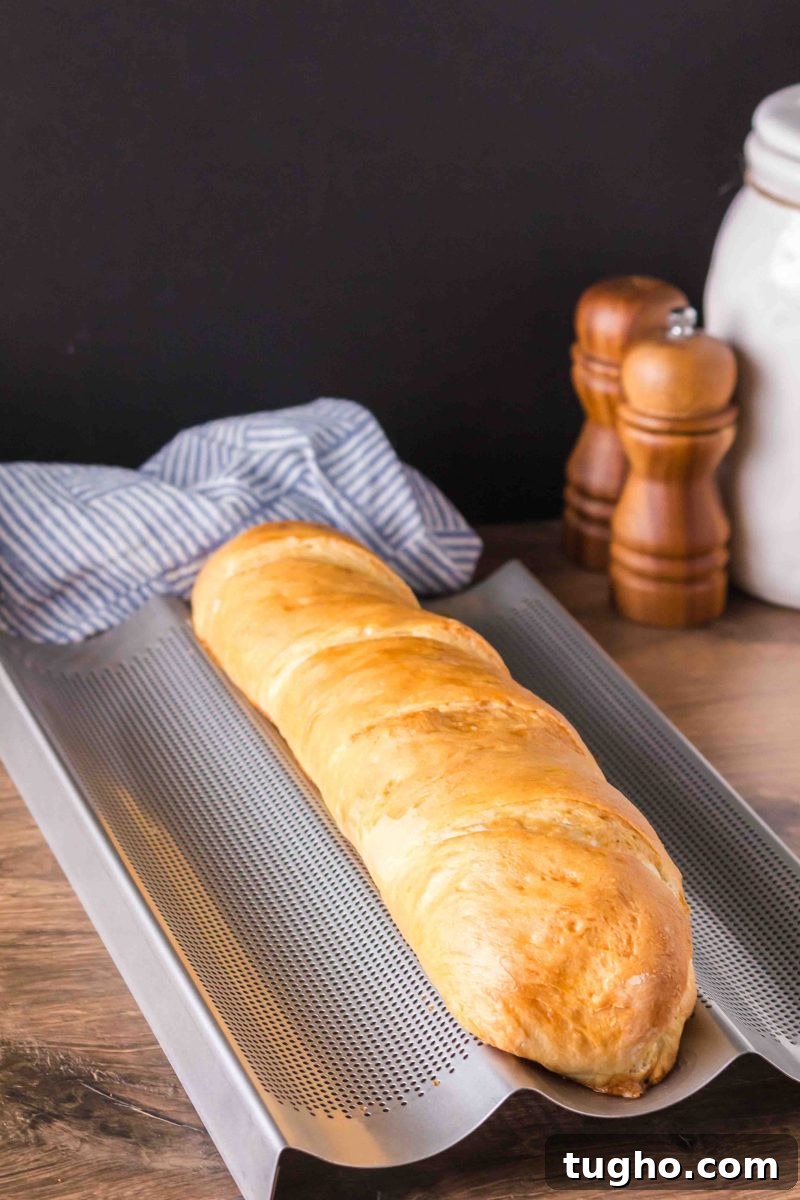French Baguette Recipe: Make Two Loaves at Home 14 A baked golden-brown French baguette fresh from the oven on a a French Baking Pan – Hostess At Heart