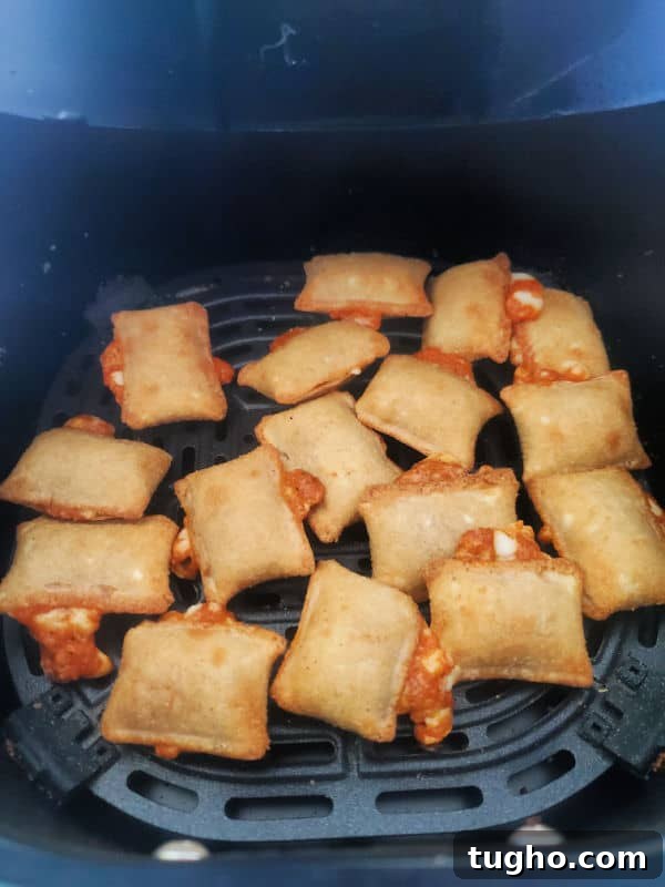 Crispy Air Fryer Pizza Rolls Recipe 5 Air fried pizza rolls in a black air fryer basket.