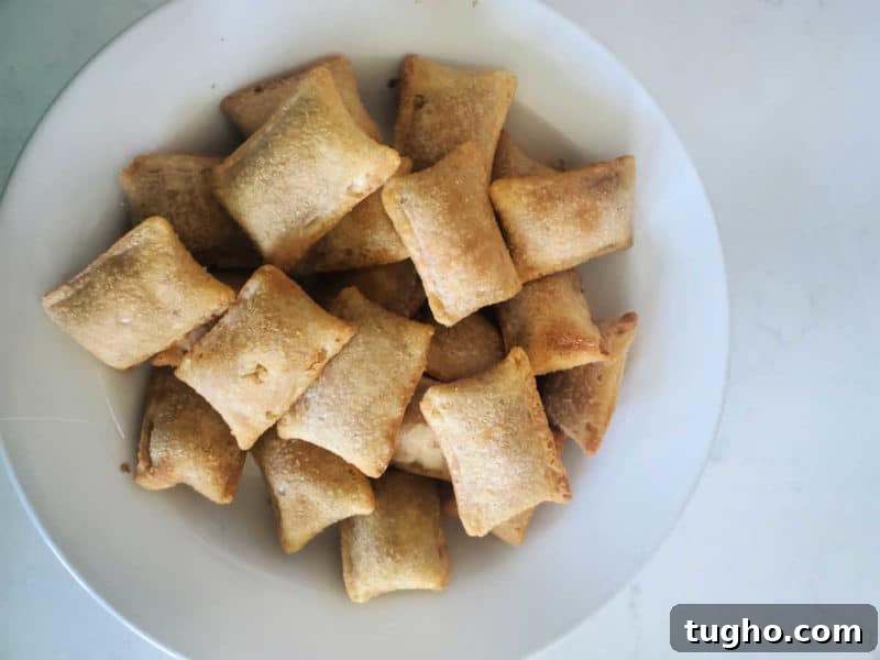 Crispy Air Fryer Pizza Rolls Recipe 7 Air fryer pizza rolls in a white bowl on a white counter.
