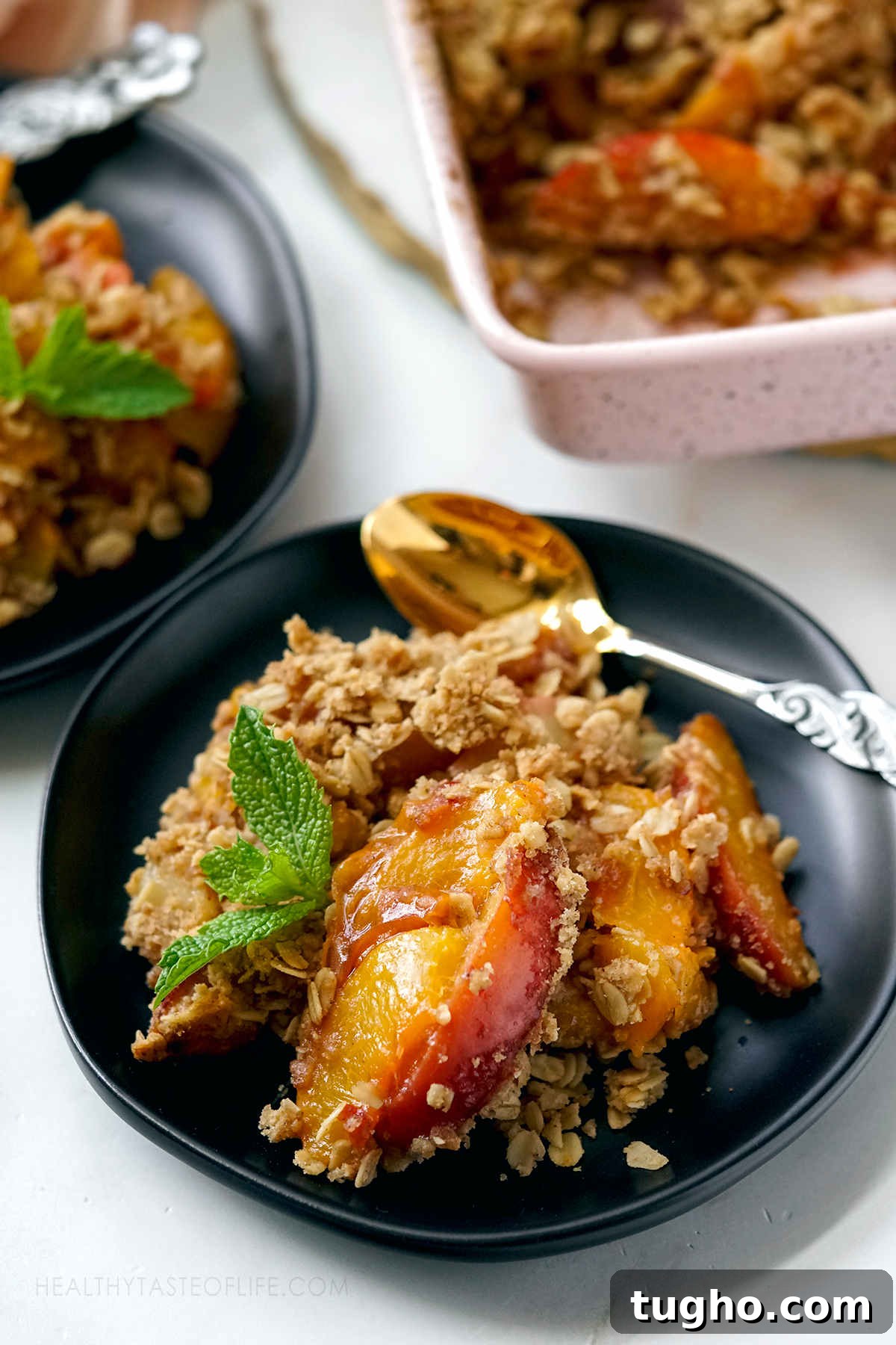 Oat-Topped Peach Crumble Recipe 3 Close up shot of peach crisp showing baked peach slices covered with crunchy oat topping.