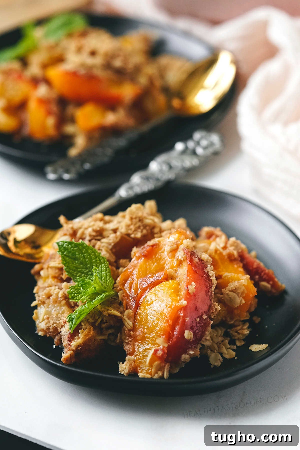 Oat-Topped Peach Crumble Recipe 8 Healthy peach crisp with oats served with a spoon.