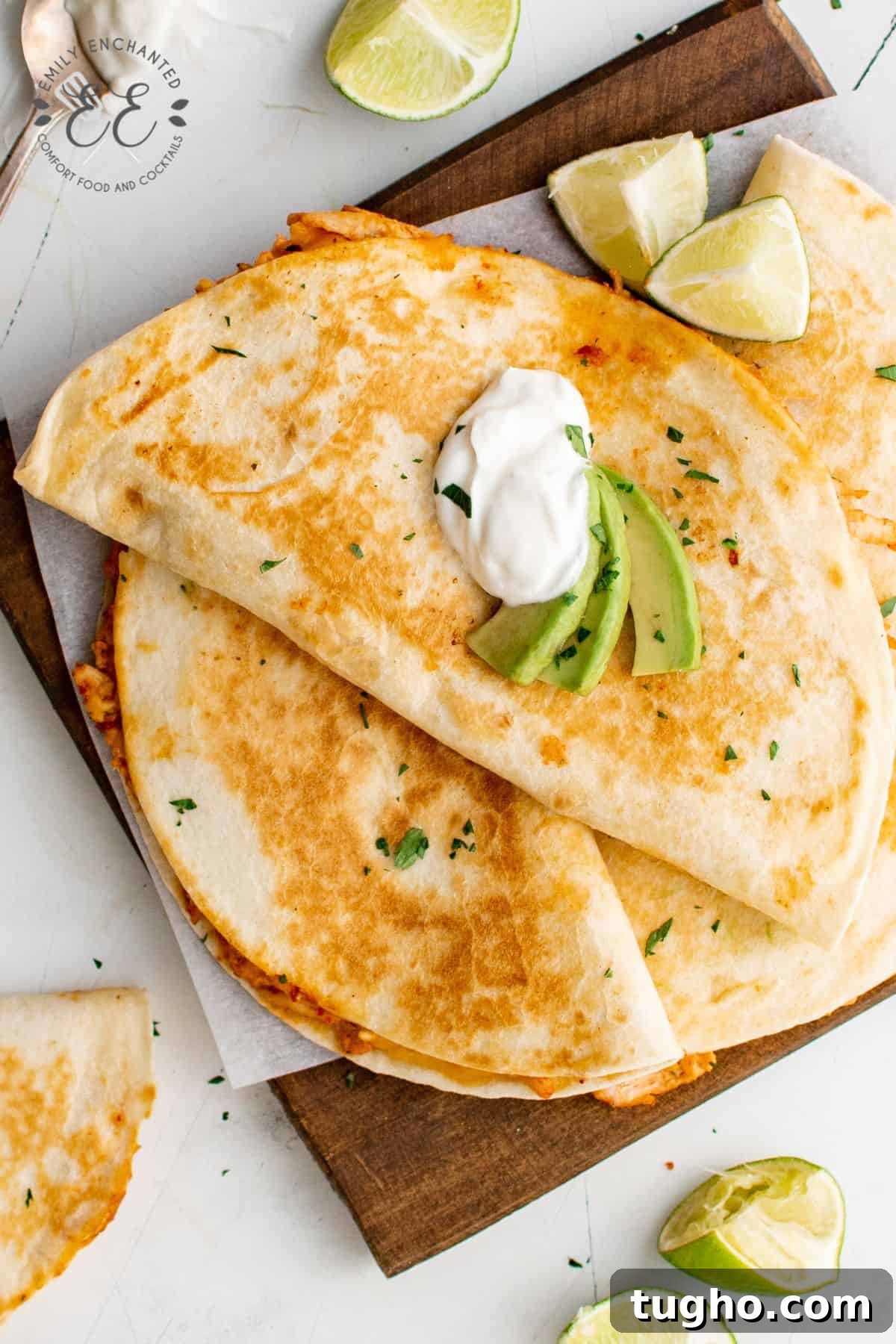 Smoky Chipotle Chicken Quesadilla Recipe 2 Chipotle Chicken Quesadillas on a cutting board with sour cream and avocado garnish