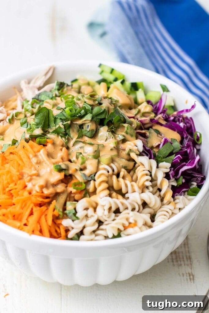 A colorful chicken pasta salad shown coated in a creamy nutty Thai dressing.