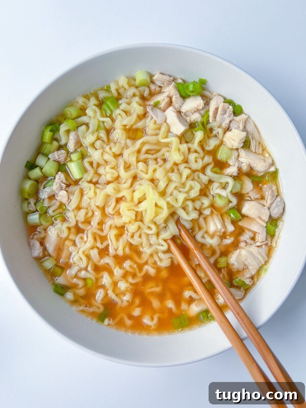 A bowl of ramen noodle soup with chicken and green onions