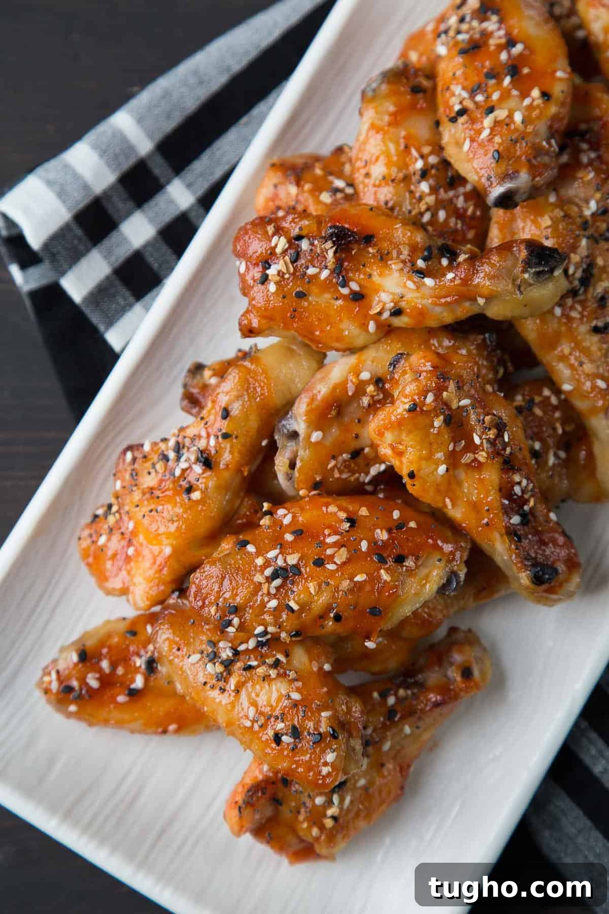 Oven-Baked Sweet and Spicy Chicken Wings Recipe 2 sweet and spicy wings topped with everything bagel seasoning on a white platter.