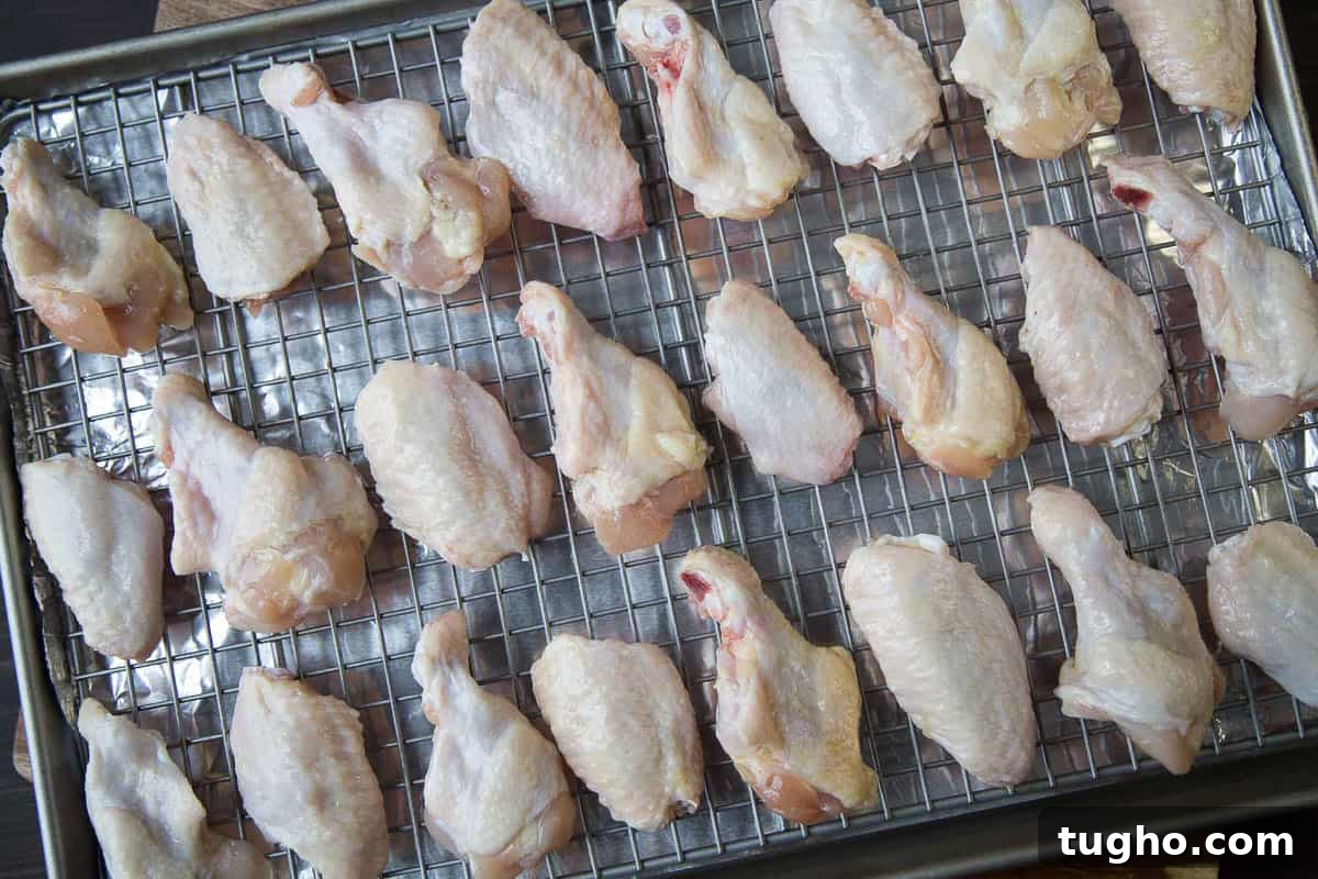Oven-Baked Sweet and Spicy Chicken Wings Recipe 5 raw chicken wings on a wire rack.