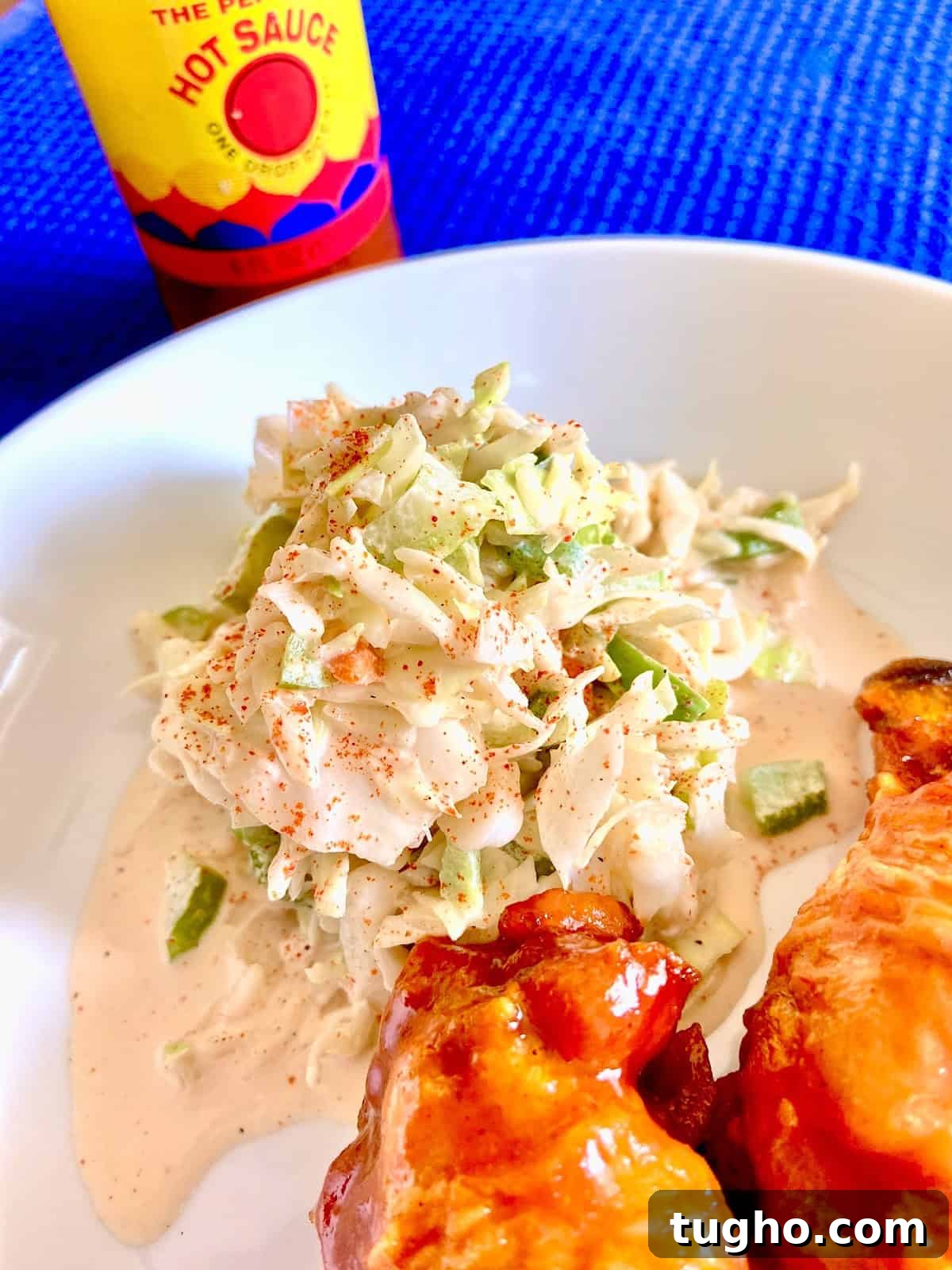 Creamy Creole Coleslaw Recipe with Zesty Remoulade 2 Creole coleslaw on white plate next to buffalo chicken wings.