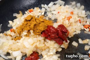 Leftover Turkey Curry with Coconut and Warm Spices 5 Chopped onions frying in a pan, with chopped chilli, tomato puree and curry powder