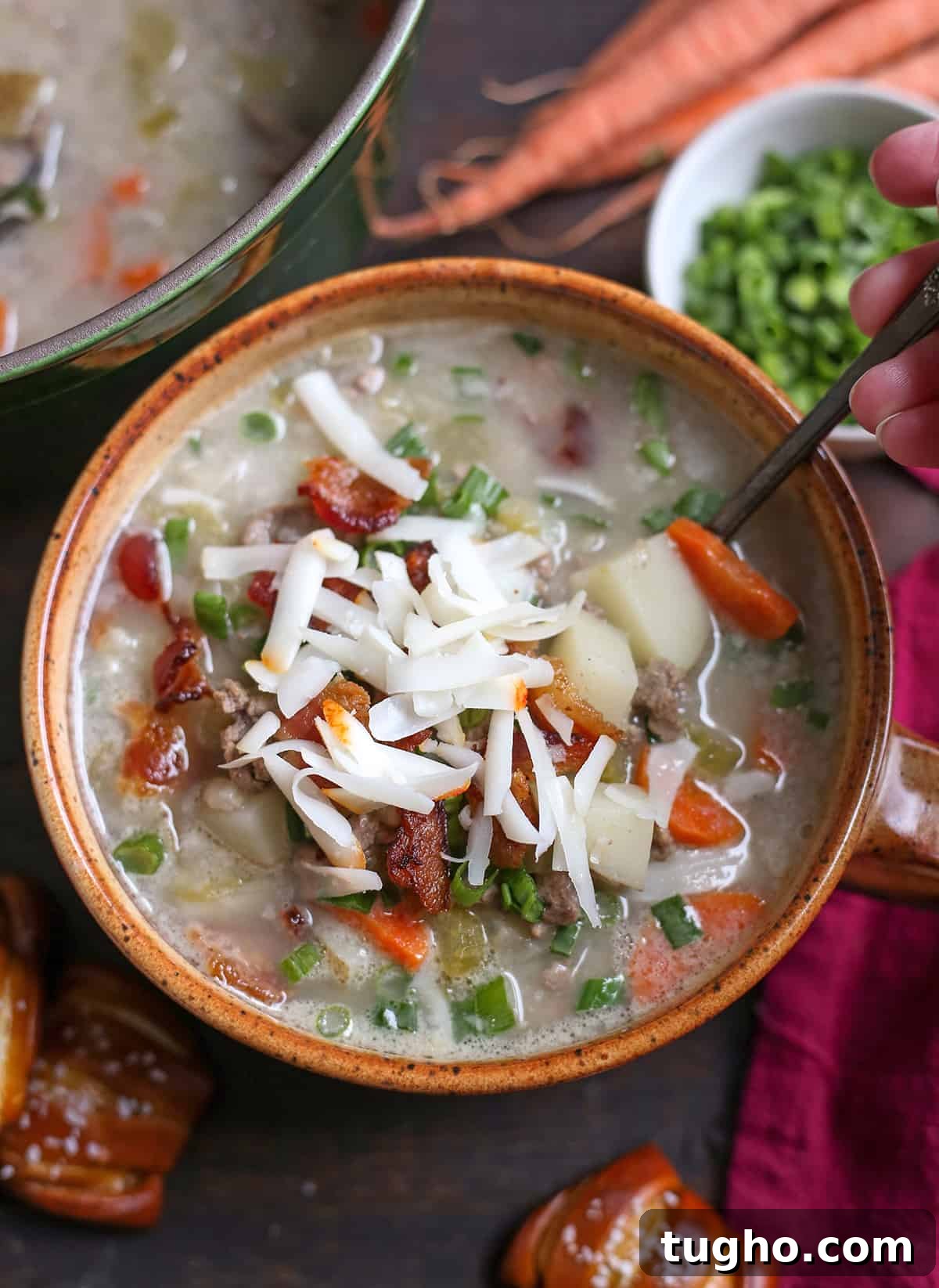 Creamy Cheeseburger Soup Recipe 5 Cheeseburger soup in a bowl with a hand taking a bite.