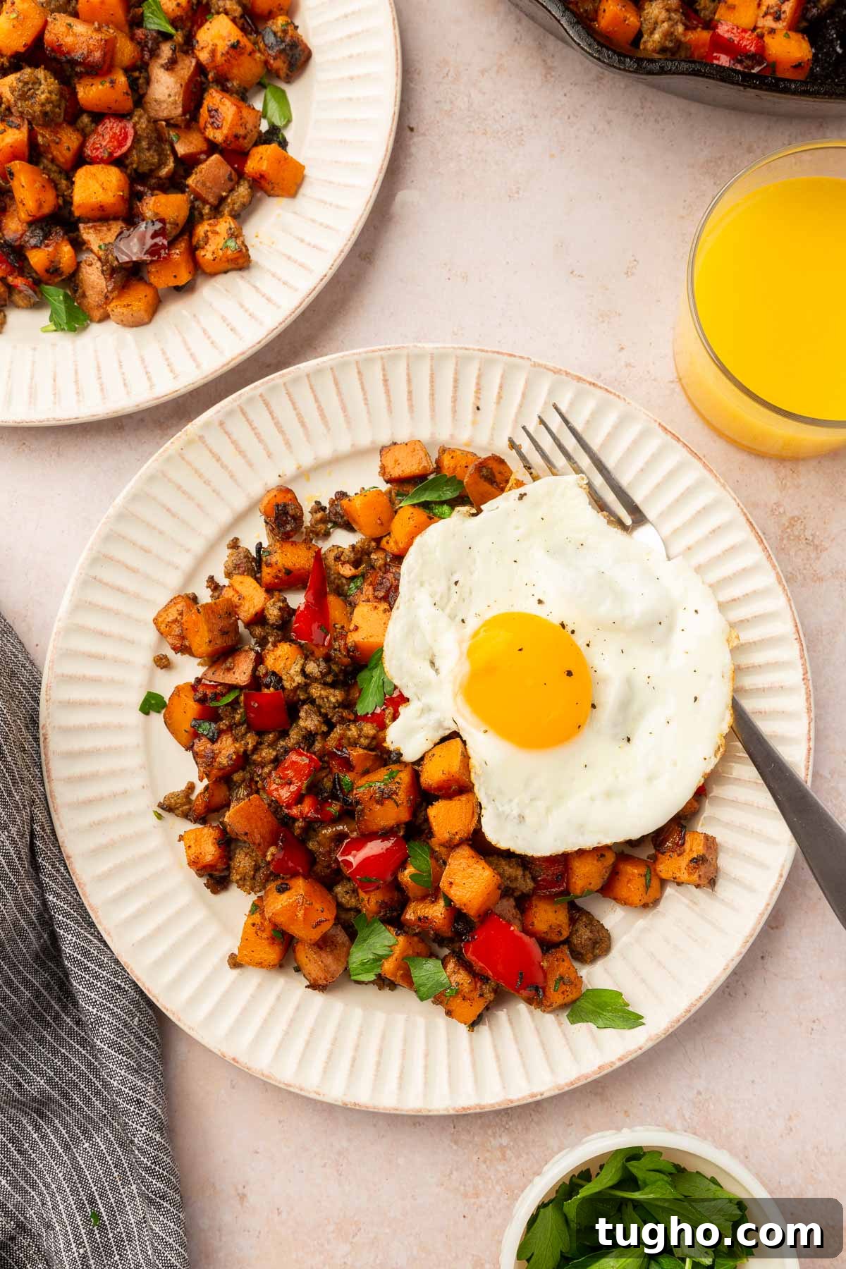 Crispy Skillet Sausage and Sweet Potato Hash 4 Multiple plates of sweet potato hash with an egg on top with a glass of orange juice to the side.