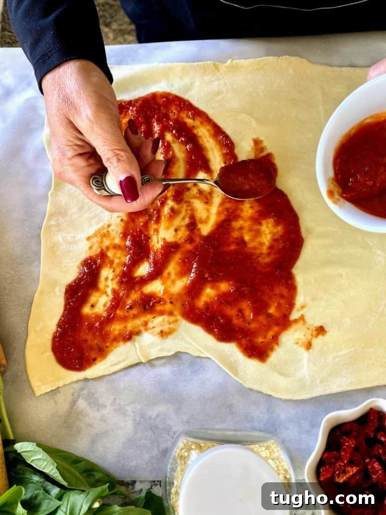 Vegan Pizza Pinwheels Recipe for Party Snacks 4 I am spreading vegan pizza sauce on the surface of the rolled-out dough.