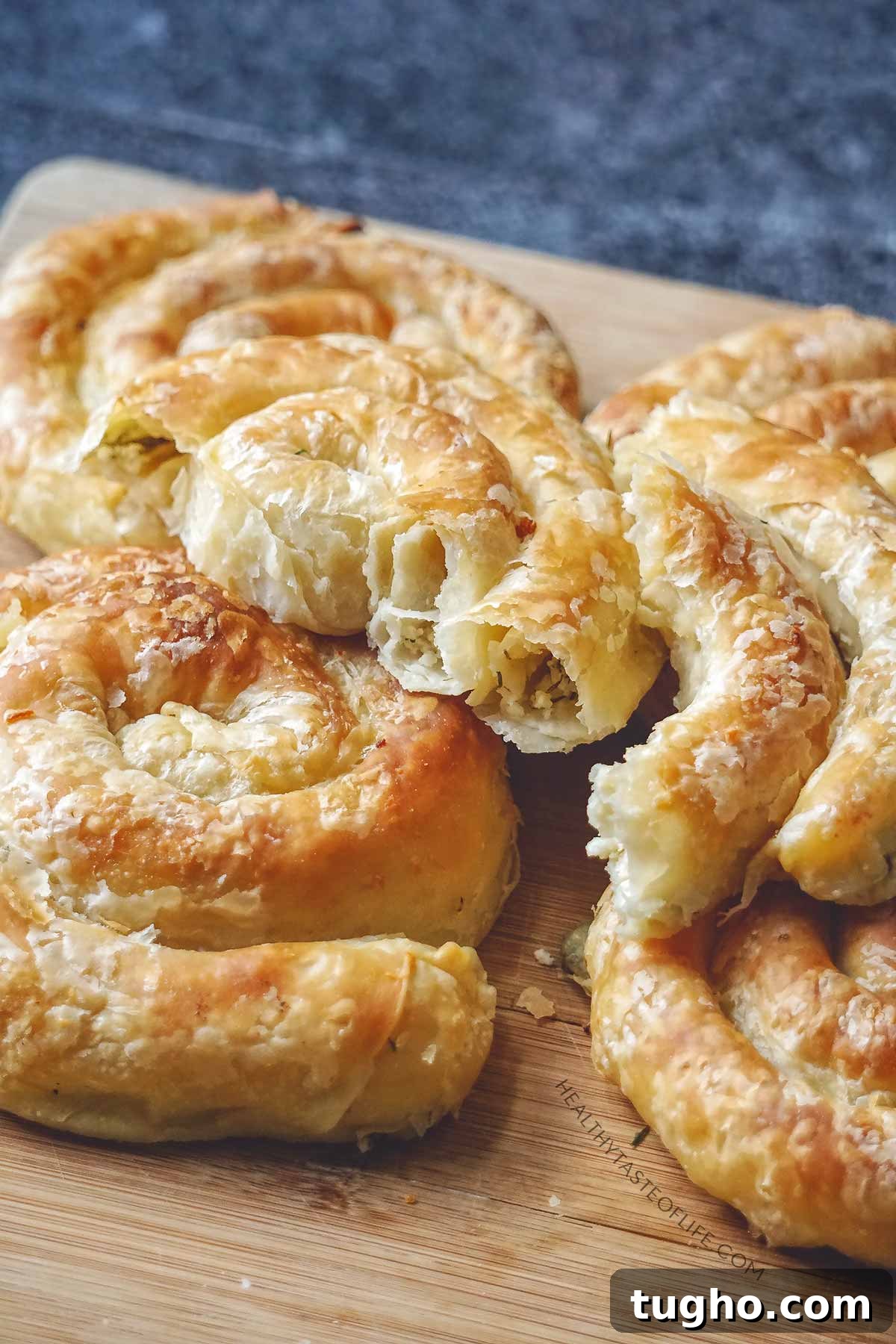 Savory Cheese Puff Pastry Pinwheels Recipe 7 Baked savory cheese puff pastry pinwheels (spirals) - flaky layers - showing texture inside resting on a board.