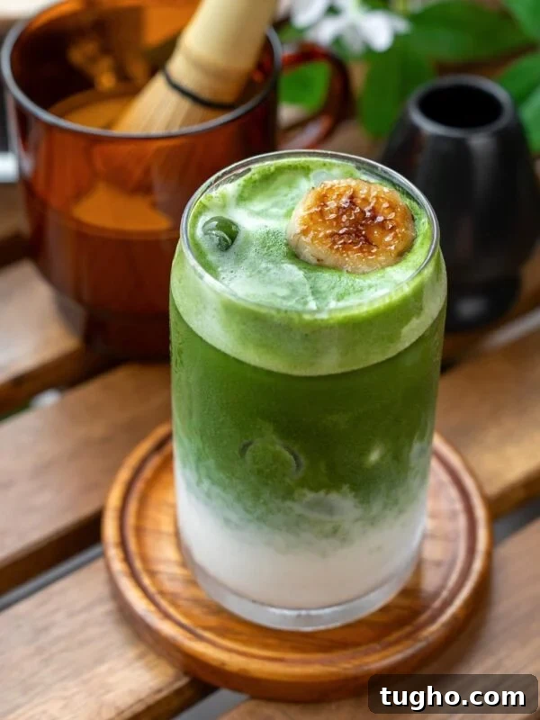 A layered banana matcha latte with a caramelized banana garnish