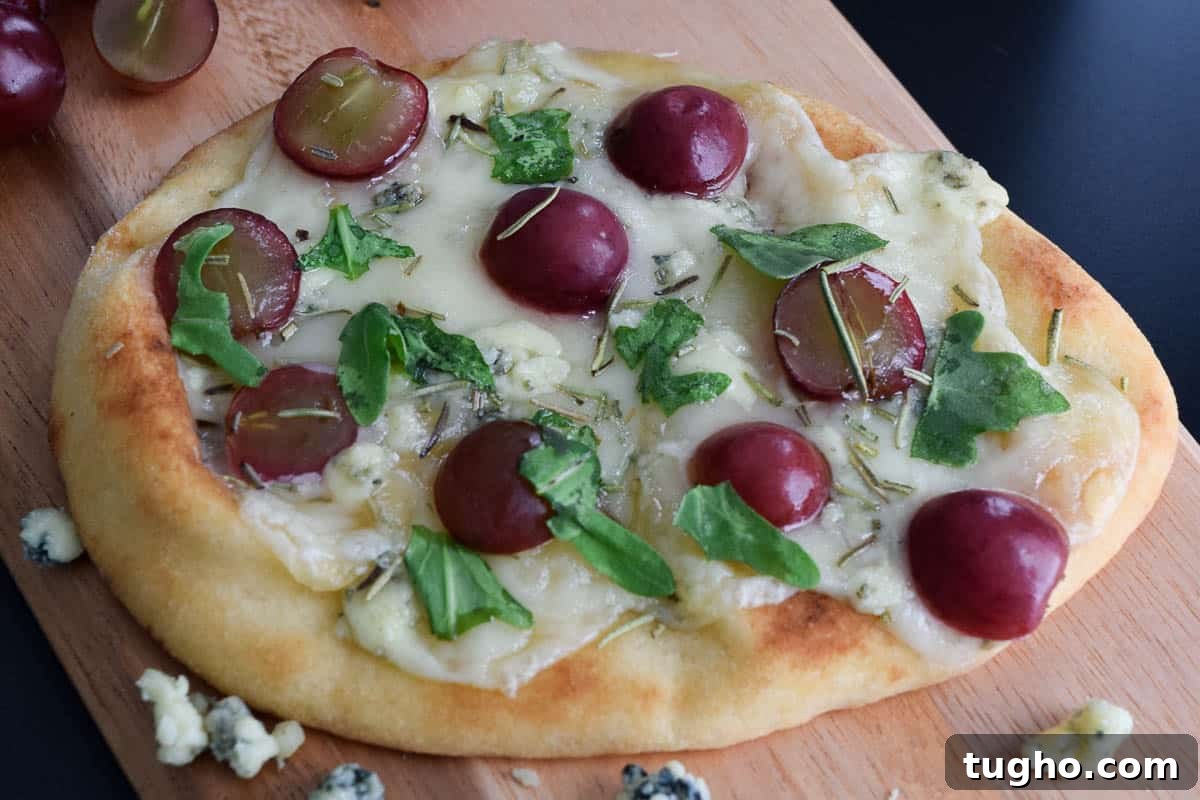 zoomed in view of flatbread with cheese grapes and arugula showing details of ingredients