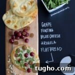 Grape Fontina Blue Cheese Arugula Flatbread on wooden serving board with title written in chalk