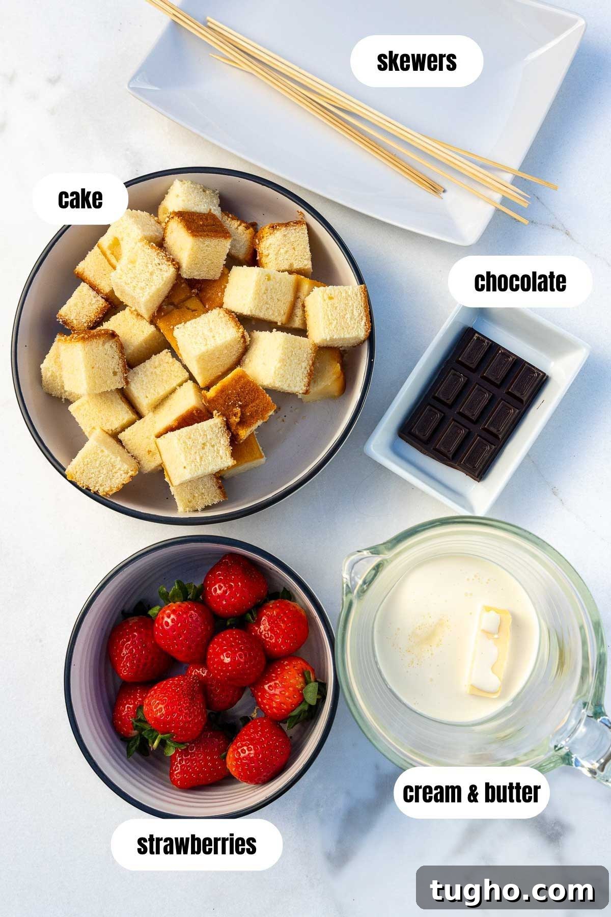 Strawberry Angel Food Cake with Chocolate Sauce 3 All the ingredients needed to make strawberry and cake skewers, labelled, including wooden skewers, strawberries, cream and butter, cubes of vanilla cake, and chocolate chunks.