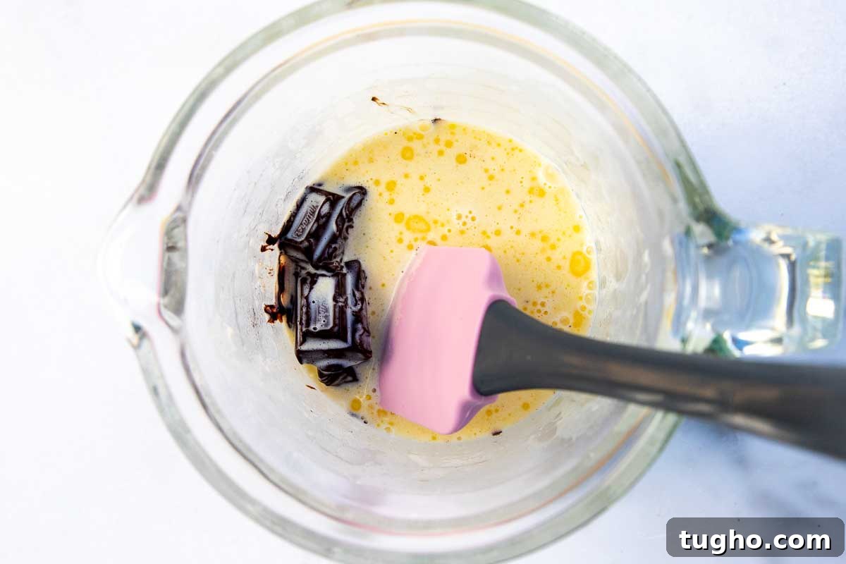 Strawberry Angel Food Cake with Chocolate Sauce 6 Overhead view of warm cream, butter and chocolate chunks in a glass jug with a pink spatula.