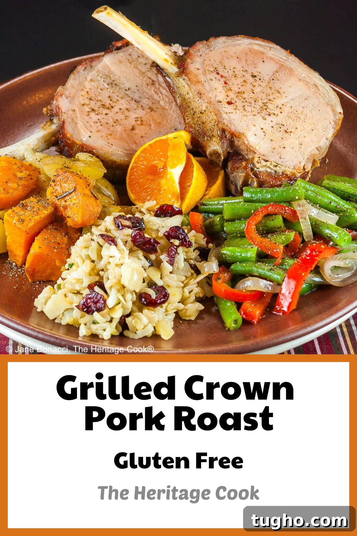 Showstopping Grilled Crown Roast of Pork Recipe 7 Grilled Crown Pork Roast sliced into chops and placed on a dark brown plate with green beans, rice pilaf, and sweet potatoes, surrounded by white candles, green garland with red accents for a festive holiday table © 2024 Jane Bonacci, The Heritage Cook.
