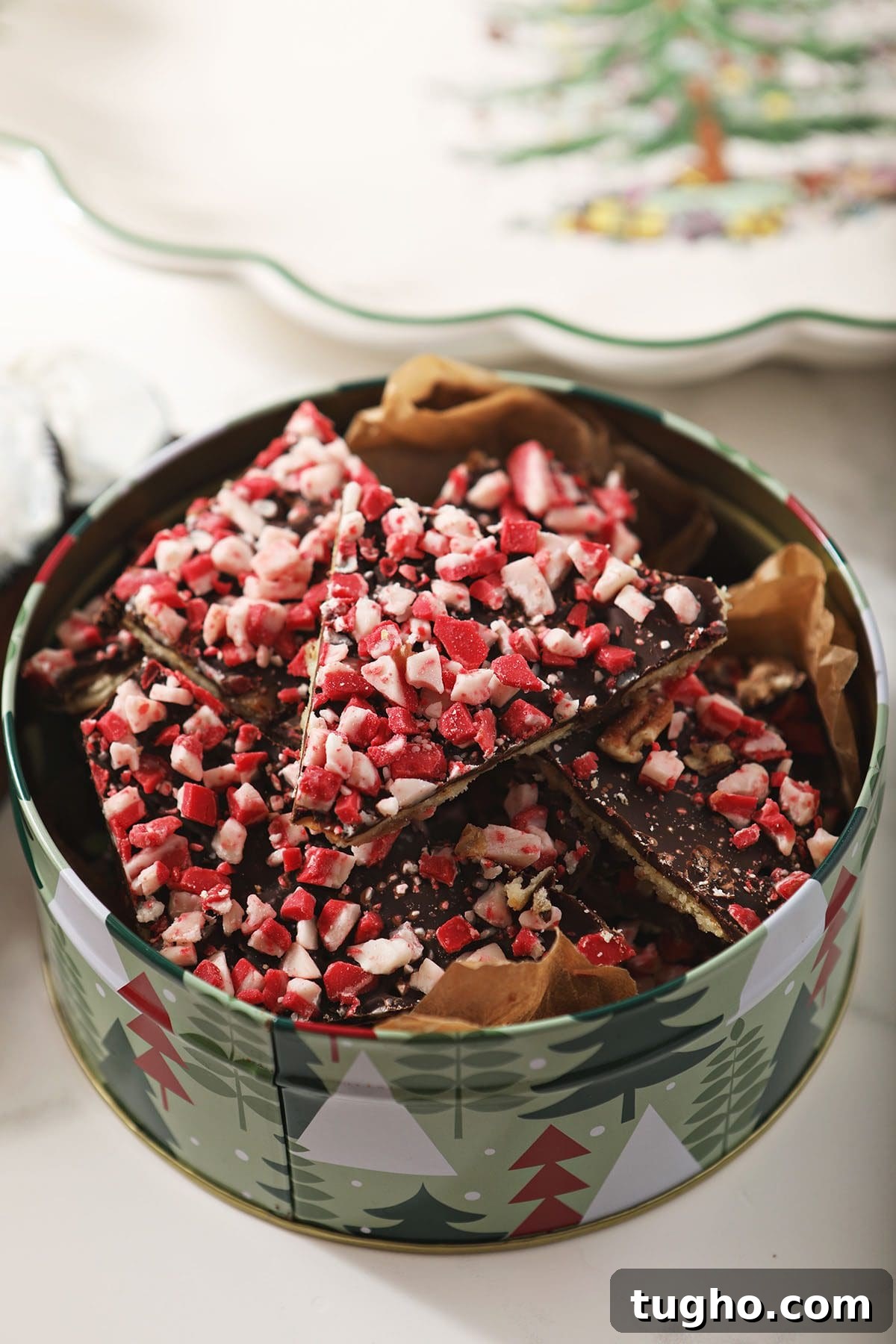 Host a Cookie Swap Party: Invitations, Recipes and Tips 5 A tin of peppermint saltine cracker toffee by a christmas platter