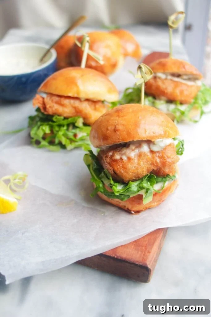 Three crispy fish sliders on a wooden board.