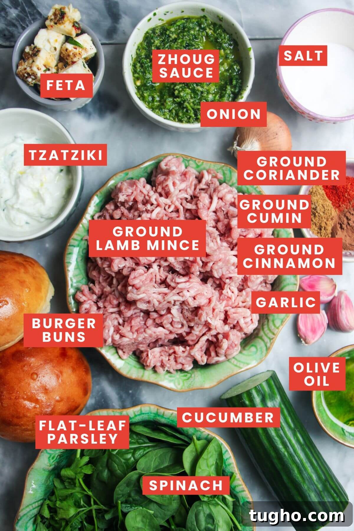 Ingredients for Greek lamb burger laid out on a grey marble background and labelled.