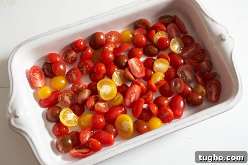 Sliced red and yellow cherry tomatoes in a white casserole dish.