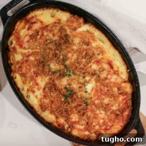 Baked delicata squash gratin in a baking dish, topped with melted cheese and breadcrumbs, golden.