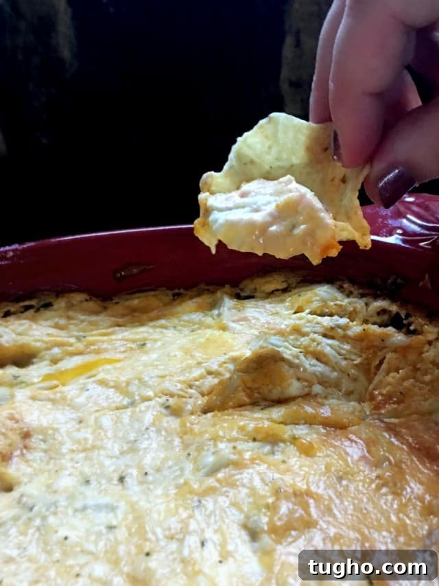 Creamy Buffalo Chicken Dip for Game Day 2 hand using scoop chip to dip up a bite of buffalo chicken dip