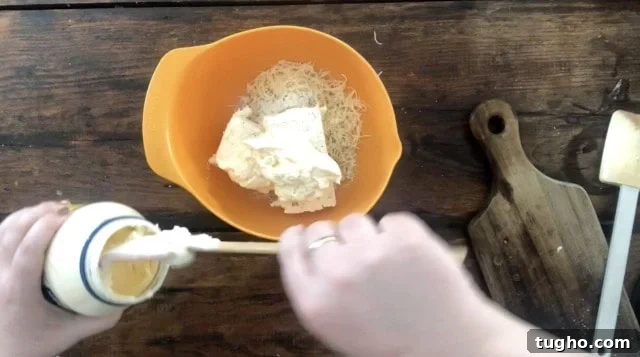 Creamy Buffalo Chicken Dip for Game Day 3 hands adding mayonnaise to an orange bowl of ingredients.