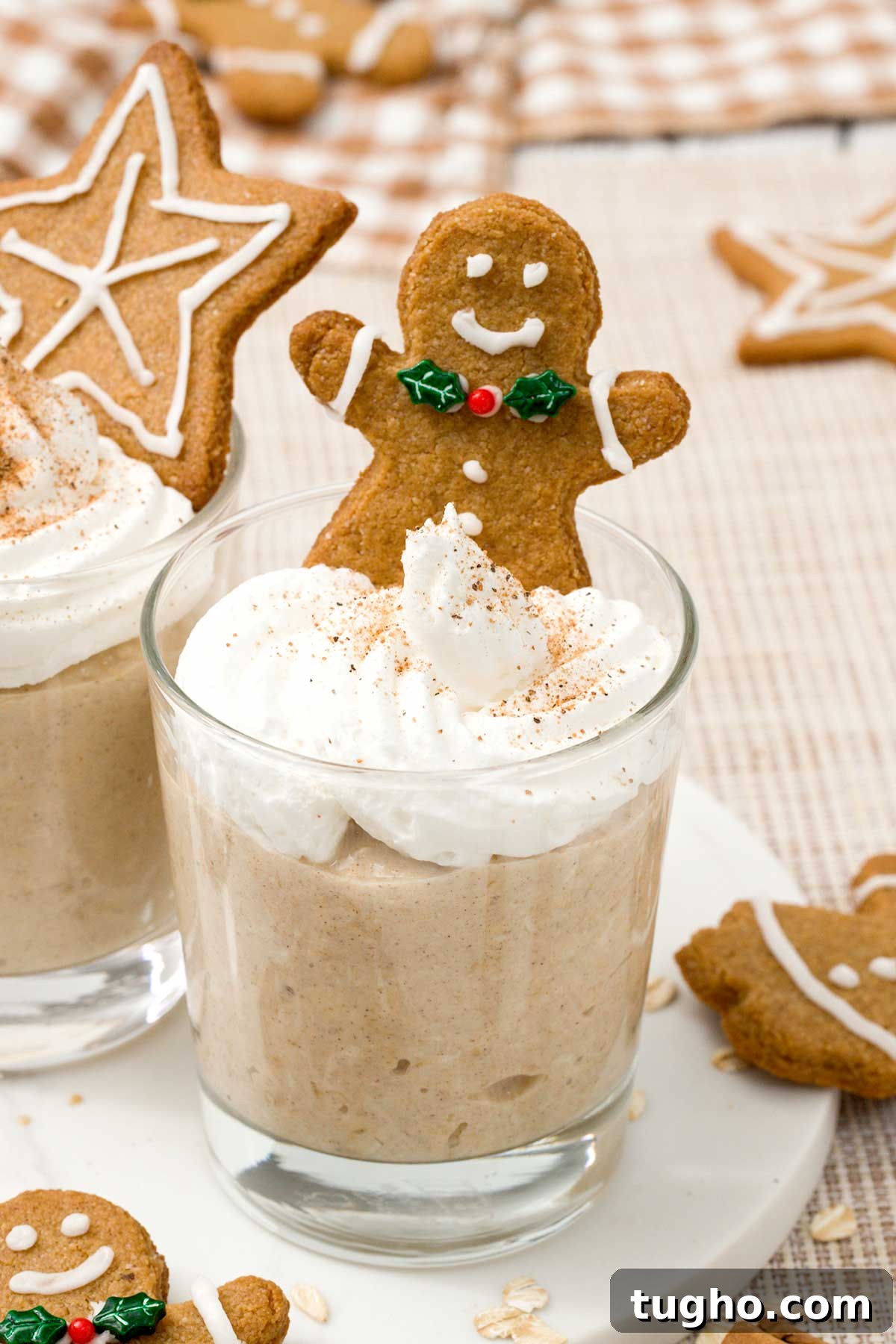 Gingerbread Overnight Oats with High-Protein Greek Yogurt 7 Close-up of a Glass with gingerbread overnight oats with whipped cream and a gingerbread cookie on top.