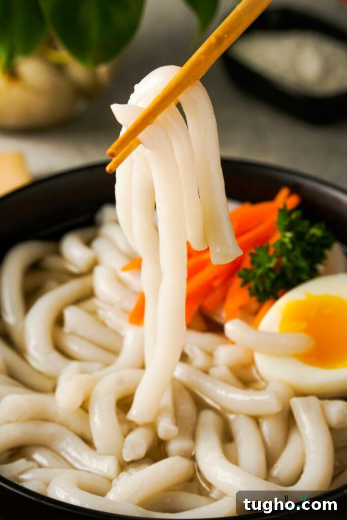 Gluten-Free Udon Noodles being held in chopsticks.