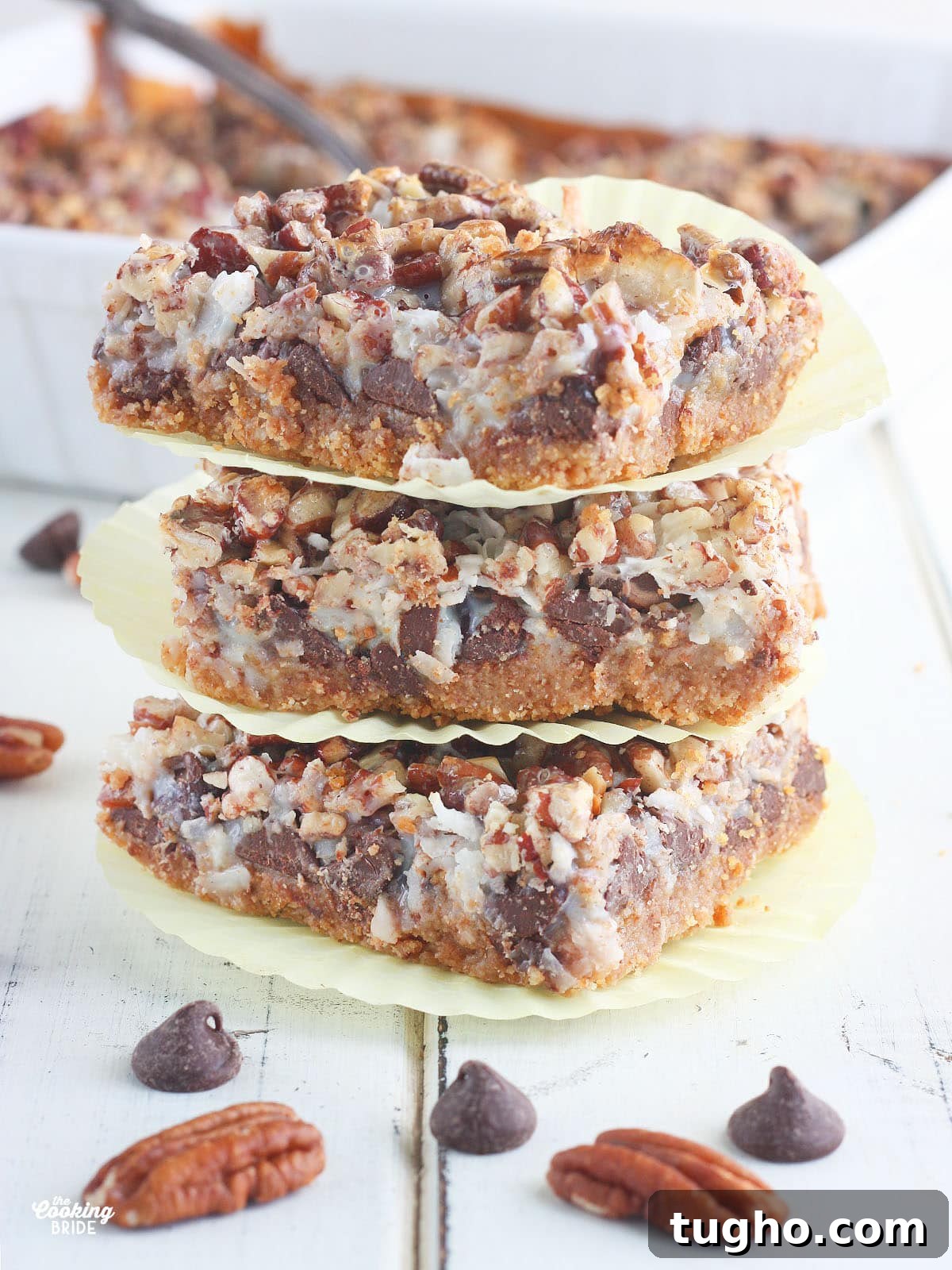 Three cut Hello Dolly bars stacked on top of each other on a white wooden table