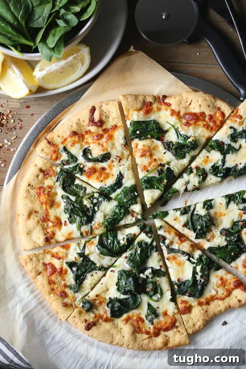 Spinach Garlic White Pizza 2 White pizza with spinach and garlic on parchment paper with lemon wedges