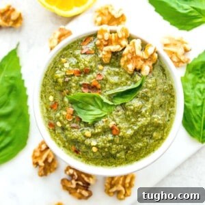 A bowl of vegan walnut pesto topped with fresh basil leaves and walnuts.