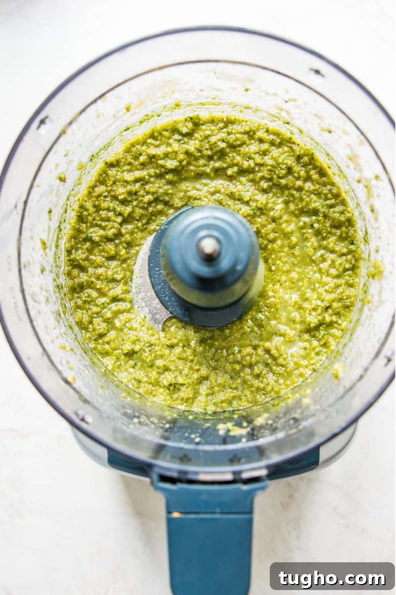 A food processor filled with a green sauce.