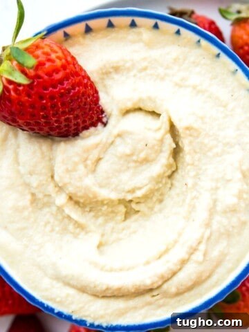 A bowl of vegan mascarpone with a fresh strawberry in it.